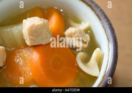 Türkei-Nudelsuppe mit Karotten in Schüssel Makro Holz Hintergrund Stockfoto