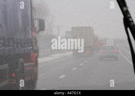 Schlechte Fahrbedingungen bei Schnee und Nässe gesehen durch Auto Windschutzscheibe auf britische Autobahn, England, UK Stockfoto