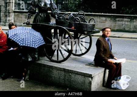 Dublin-Mann sitzt lesen die Zeitung neben der Statue von Molly Malone 1999 Stockfoto