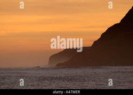 Klippen bei Dämmerung fallen in eine energetische Meer beleuchtet von warmen Farbtönen von einem nebligen Sonnenaufgang alte Spitze Klippe am Ravenscar in North Yorkshire Stockfoto