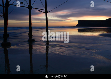 Niedrige Schlüsselbild auf der Suche durch die Beine des alten Pier am Strand von Saltburn in North Yorkshire mit Blick auf Jagd Cliff Stockfoto