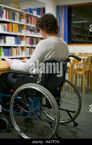 Behinderter Mann liest in Bibliothek Stockfoto