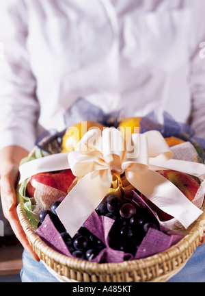 Mid section view of a woman holding a basket of fruit Stockfoto