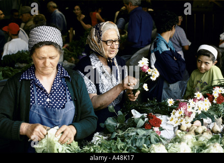 Siebenbürgen Rumänien Kind am Markt beobachten zwei ältere Frauen Standinhaber Blumen bereiten Salat 1998 Stockfoto