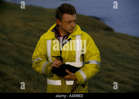 Retter hält eine Ente bedeckt in Öl, nachdem ein Tanker vor Shetland-Inseln sank Stockfoto