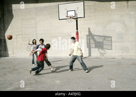 Vier junge Männer und eine junge Frau spielen basketball Stockfoto