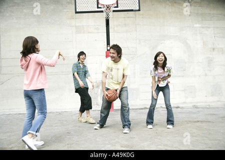 Zwei junge Männer mit zwei jungen Frauen Basketball spielen Stockfoto
