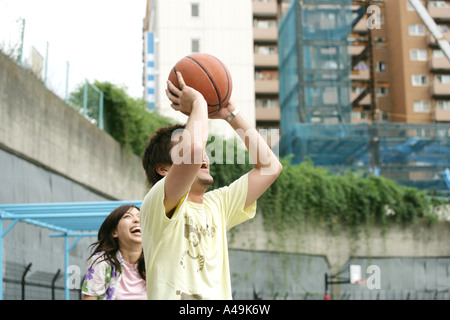 Nahaufnahme eines jungen Mannes hält einen Basketball mit einer jungen Frau, die hinter ihm steht Stockfoto