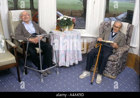 2 ältere Männer sitzen auf Sesseln durch Fenster in alten Menschen s home northampton Stockfoto