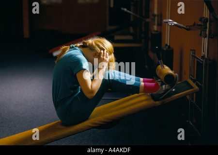 eine Frau sitzt zusammengerollt direkt auf einem Tilt Board dabei Sit Ups beim Fitness-training im Sportzentrum in hackney, London Stockfoto