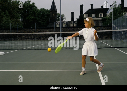 Ein junges Mädchen lernt gern Tennis mit einem Kunststoff Schläger mit Nachhilfeunterricht, London, UK. Stockfoto