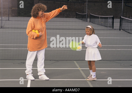 Ein junges Mädchen lernt gern Tennis mit einem Kunststoff Schläger mit Nachhilfeunterricht, London, UK. Stockfoto