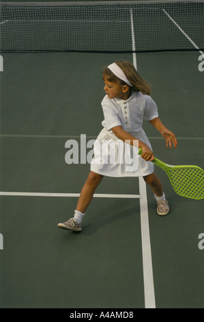 Ein junges Mädchen lernt gern Tennis mit einem Kunststoff Schläger mit Nachhilfeunterricht, London, UK. Stockfoto