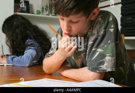 Ein acht Jahre alter Junge seine Hausaufgaben Mathe zu Hause mit seiner Schwester im Hintergrund ihre eigenen Hausaufgaben, Februar 2006. Stockfoto