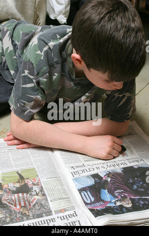 Ein acht Jahre alter Junge lesen den Sportteil der London Evening Standard auf dem Boden zu Hause, Februar 2006. Stockfoto