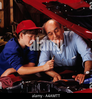 Ein Großvater und Enkelin überprüfen eine Zündkerze, während der Arbeit an einem Oldtimer in der garage Stockfoto