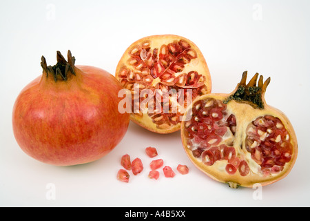 Ein ganzer und zwei halbe Granatäpfel zeigen Samen und entfernt Auf weißem Hintergrund Stockfoto