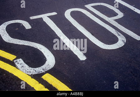 Detail der schwarzen Asphaltstraße Oberfläche mit Stop gemalt und Bestandteil einer gekrümmten doppelt Gelb keine Parkplatz-Linie Stockfoto