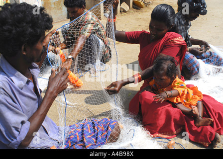 Abbildung des indischen Stammes-Fischer und Frau Fischer reparieren ihre Netze in der Nähe von Chennai Tamil Nadu, Indien Stockfoto