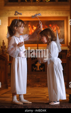 ENGEL SETZEN AUF IHRE HALOS VOR EINER GRUNDSCHULE KRIPPE SPIELEN IN EINER KIRCHE SOMERSET UK Stockfoto