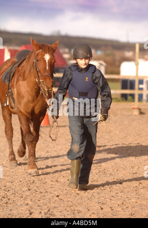 EIN KIND FÜHRENDEN HOCHSCHULEN PFERD MIT HEU BEI EINER REITSCHULE SOMERSET UK Stockfoto