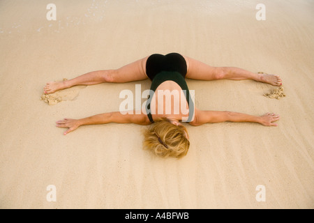 schöne 50 Jahre alte Frau beim Yoga am Strand Stockfoto