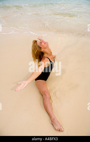 schöne 50 Jahre alte Frau beim Yoga am Strand Stockfoto