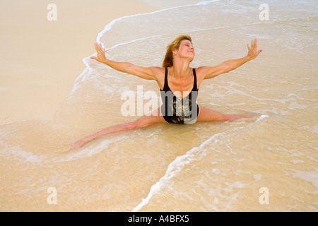 schöne 50 Jahre alte Frau beim Yoga am Strand Stockfoto