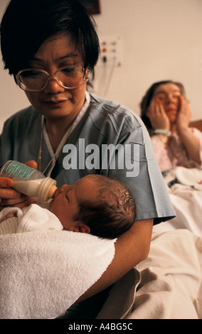 Mutterschaft-Einheit, Homerton Hospital, London, England: Eine Hebamme gibt ein neugeborenes Baby seinen ersten Schluck Milch. Stockfoto