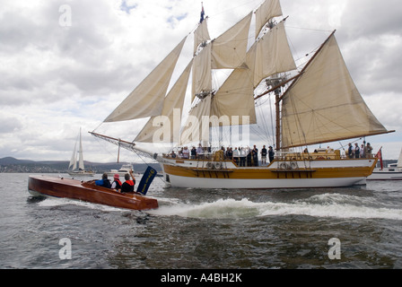 Ein Motorboot Motoren vorbei an der quadratischen manipulierten Lady Nelson während der Parade des Segels auf dem australischen hölzernen Boot Festival 2007 Stockfoto