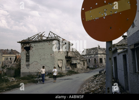 Vukovar, Kroatien, unter serbischer Kontrolle, Februar 1992: Menschen zu Fuß entlang einer Straße von ausgebrannten Überreste von Häusern mit Granatfeuer entsteint Stockfoto