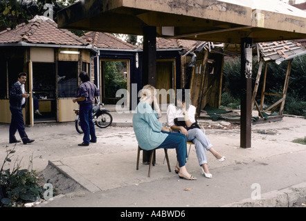 Vukovar, Kroatien, unter serbischer Kontrolle, Februar 1992: zwei junge Frauen zu chatten, indem eine Wartehalle. hinten sind zerstörten Geschäfte und Stände Stockfoto