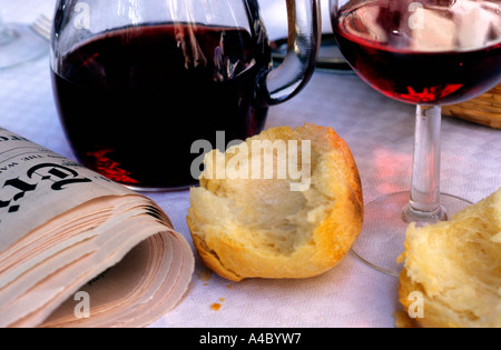 Brot, ein Glas Rotwein und eine gefaltete New York Times auf einem Tisch in einem französischen Bistro oder Café. Nahaufnahme. Paris Frankreich. Keine Personen Stockfoto