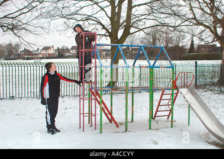 Jungen auf einem Klettergerüst spielen. Eine Schnee bedeckt Spielplatz In einem öffentlichen Park. Stockfoto