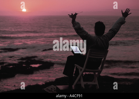 Business-Mann mit Laptop und Handy Sonnenuntergang über Pazifischen Ozean Stockfoto