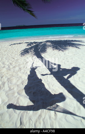 Paar entspannende Hängematte und auf Palme Silhouette über weißen Sandstrand Stockfoto