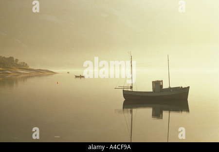 Kleines Fischerboot verankert im norwegischen Fjord mit Mann im Ruderboot Stockfoto