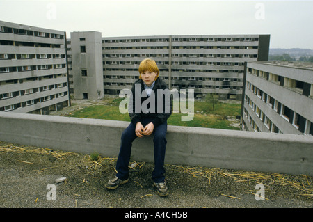 TEENAGER SITZT AUF MÄUERCHEN VOR VERLASSENEN SIEDLUNG ERWARTET FÜR DEN ABRISS. NETHERLY, LIVERPOOL. Stockfoto