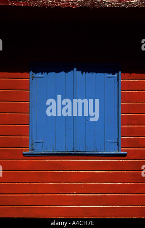 Buenos Aires, Argentinien. Bunt bemalten blauen Fensterläden in einer roten Wand im Stadtteil La Boca. Stockfoto