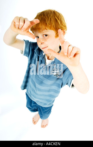 Ginger Haired junge gekleidet in blau, die Hand in seine Hand als Rahmen Stockfoto