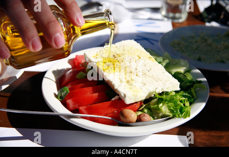 Öl auf griechischer Salat gegossen Stockfoto