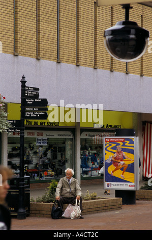 ÄLTERE MÄNNLICHE SHOPPER, SITZEN, RUHEN, MIT VOLLEN EINKAUFSTÜTEN GEFILMT ONN TV ÜBERWACHUNGSKAMERAS, KING'S LYNN, 1994 Stockfoto