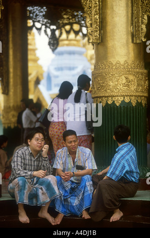 Drei junge Männer sitzen auf den äußeren Stufen der Shwedagon Pagode Tempel, Yangon, Rangun, Myanmar, Burma Stockfoto