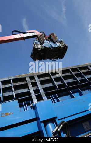 Eine zerdrückte Auto wird von einem Kran auf einem Schrottplatz, zerquetscht zu werden aufgehoben. Stockfoto