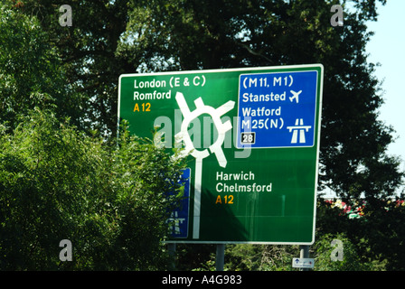 Mangelnde Wartung der grünen Richtungsschilder zur M25 an der Anschlussstelle 28, teilweise verdeckt durch bewachsene Sträucher Brentwood Essex England UK Stockfoto