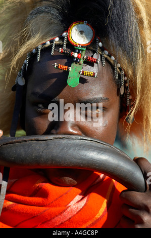 Eine Nahaufnahme von einem Masai Mann bläst in eine Antilope Horn in der Masai Mara-Village in Kenia. Stockfoto