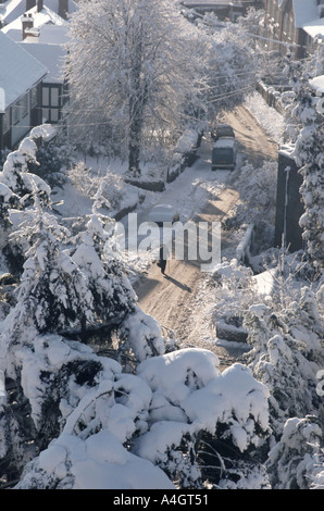 Nach starkem Schneefall blickte man auf eine Wohnstraße mit einem alten älteren Menschen, der auf einer hügeligen Straße mit einem Wanderstock Brentwood Essex UK herumlief Stockfoto