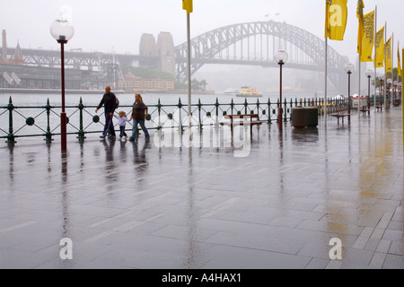 Familie Mutter Vater und Kind zu Fuß im Regen in Circular Quay Sydney Australia an einem verregneten Tag Stockfoto