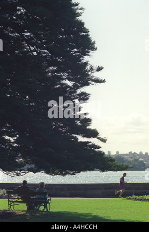 Ein älteres Ehepaar beobachten junge Jogger im Park, Sydney, Australien Stockfoto