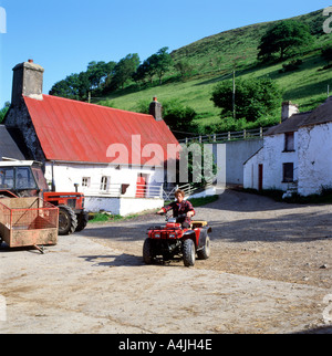 Ein Waliser Bauern auf Quad Bike im Hof, außerhalb seines traditionellen Steinhaus in Carmarthenshire Wales. UK KATHY DEWITT Stockfoto